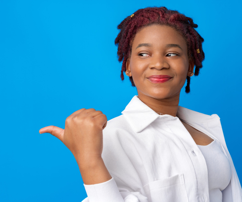 Young african american woman pointing to copy space against blue background, close up